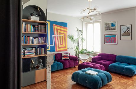 Vibrant, eclectic living room with geometric wall art, plush sofas, and a statement chandelier.