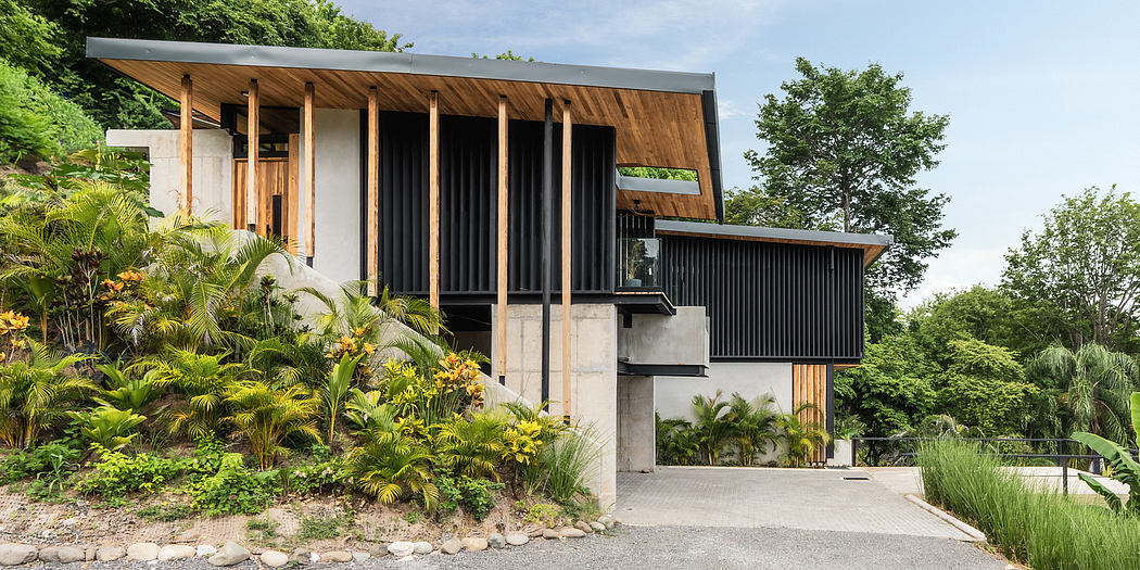 A modern, wood and concrete house nestled in a lush, tropical garden.