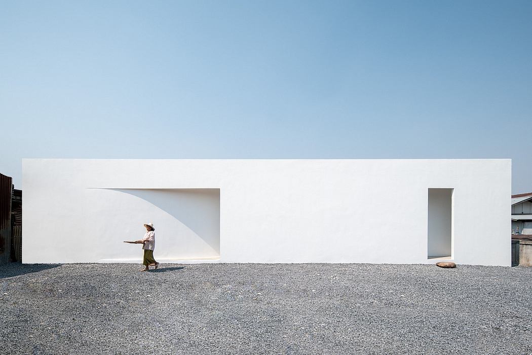 Clean, minimalist architecture with stark white walls, open spaces, and a person standing in the foreground.