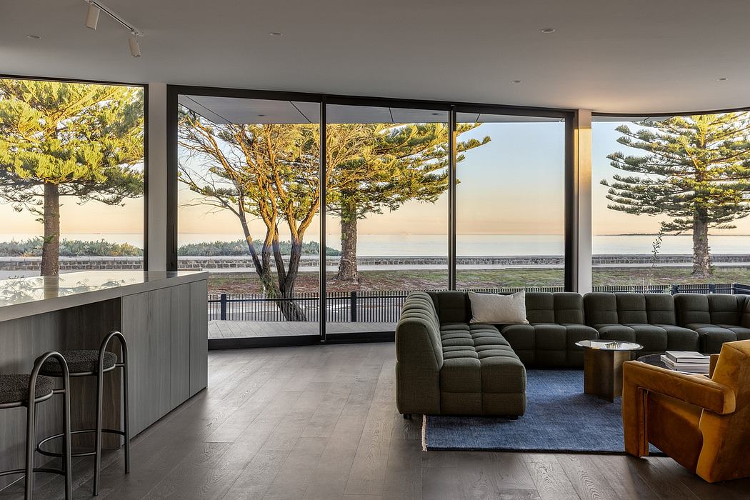 Spacious modern living room with panoramic views through large windows and pine trees.