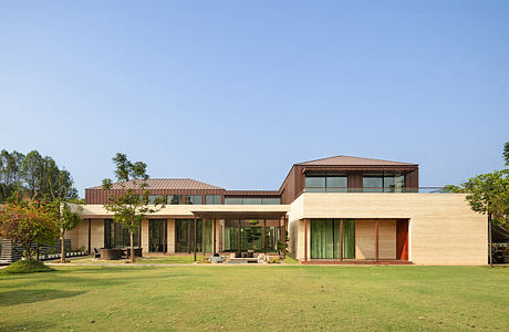 Modern residential building with varied rooflines, extensive glazing, and landscaped lawn.