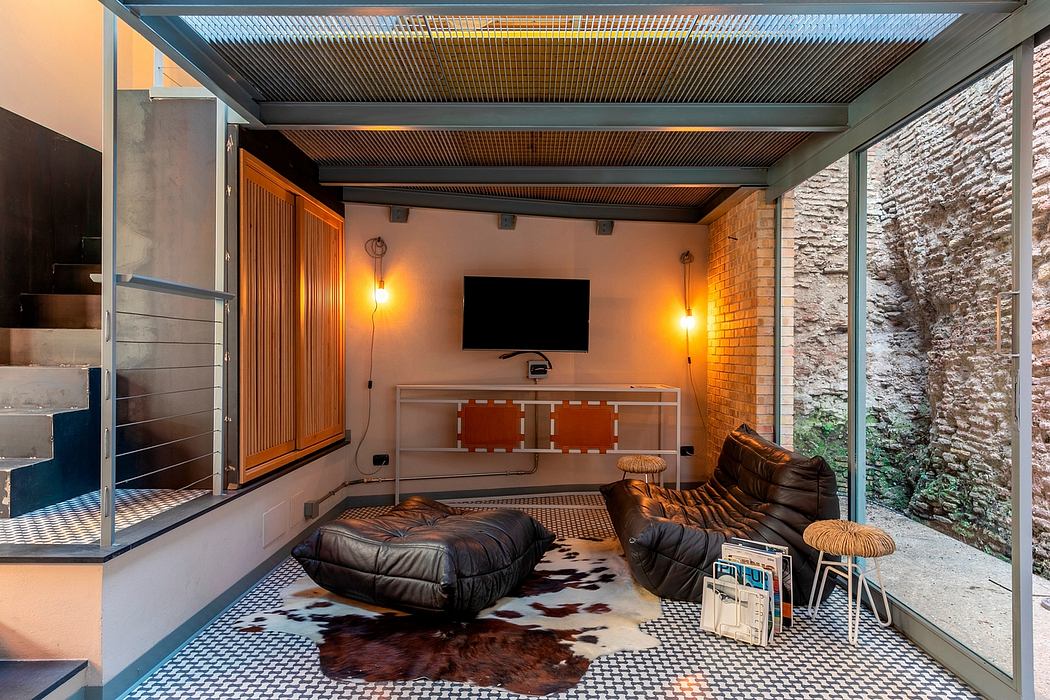 A modern, open-plan interior with industrial-style ceiling, brick walls, and cozy furnishings.