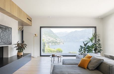 Minimalist living room with a wall-to-wall panoramic window overlooking a mountainous landscape.