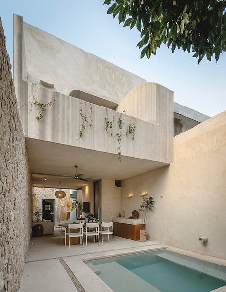 A modern, minimalist home with a small pool, concrete walls, and an open living area.