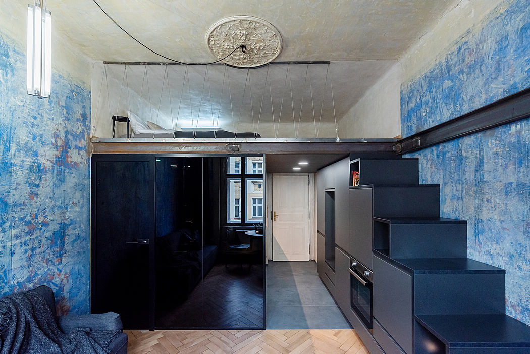 A modern, compact studio apartment with sleek black furnishings and vibrant blue walls.