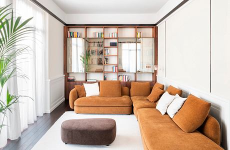 Warm, cozy living room with wood shelving, plush orange sofa, and potted plant.