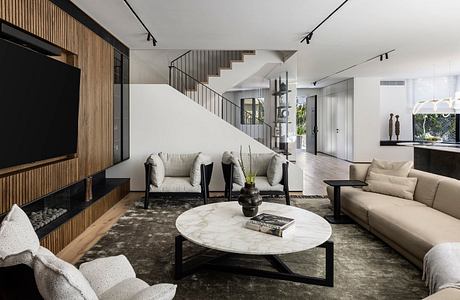A modern, open-concept living space with a large marble coffee table, plush sofas, and a prominent wooden accent wall.
