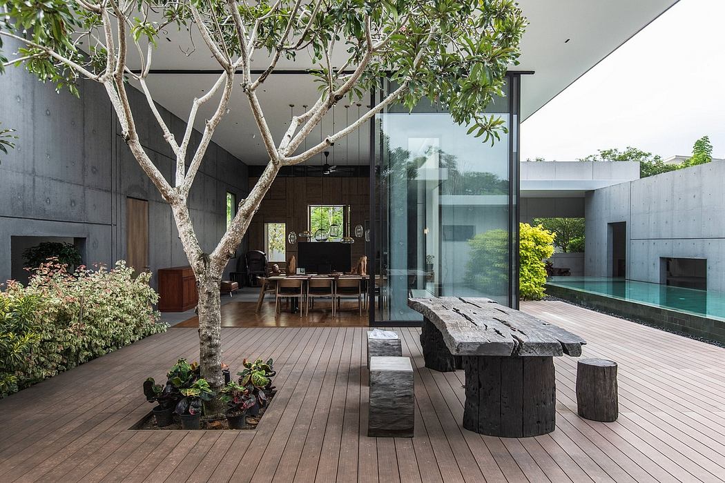 Minimalist concrete architecture with a lush garden, wooden deck, and glass walls.
