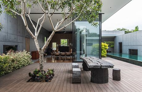 Minimalist concrete architecture with a lush garden, wooden deck, and glass walls.