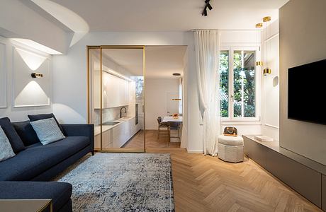 Minimalist apartment interior with clean lines, large windows, and herringbone wooden floors.