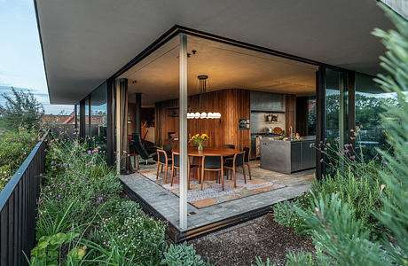 A modern, open-concept home with wooden accents, floor-to-ceiling windows, and a lush outdoor garden.