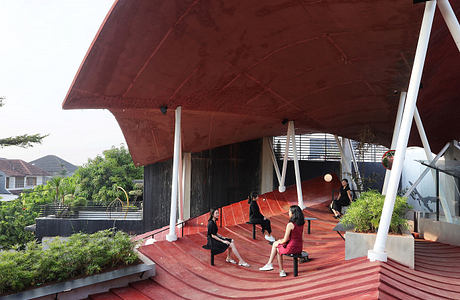 Striking red-toned architectural structure with stepped seating and lush landscaping.