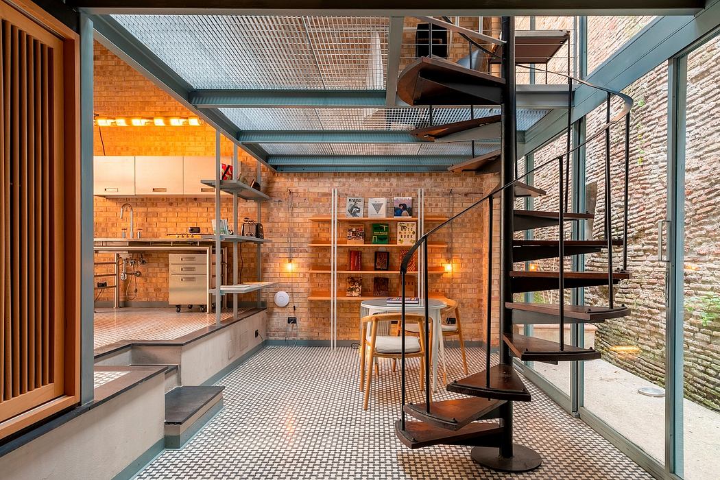 Rustic industrial-style kitchen and dining area with exposed brick walls, metal beams, and spiral staircase.