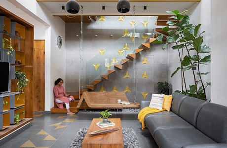 A modern living space with geometric, triangular lighting fixtures and a wooden staircase.