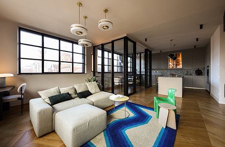 Modern open-concept living space with large windows, geometric rug, and pendant lighting.