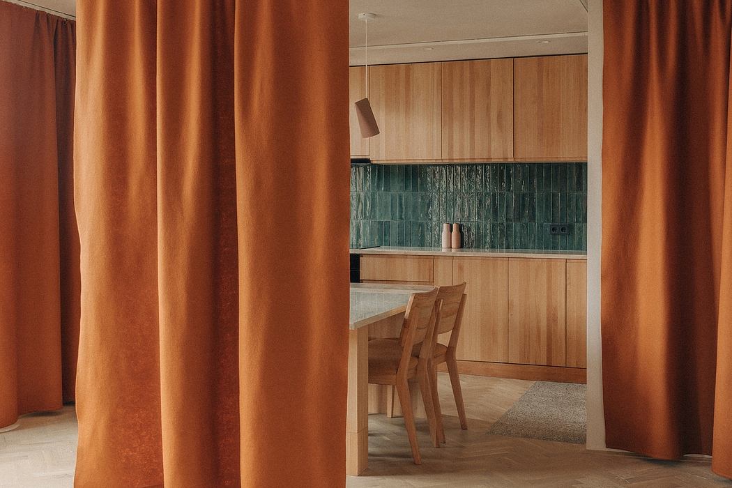 Warm, wooden kitchen with vibrant orange curtains and textured tile backsplash.