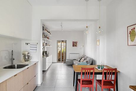 Bright, modern kitchen with open-concept living area, wooden dining table, and pendant lights.