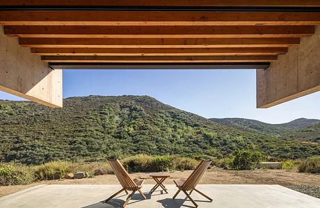 Rustic wooden beams frame a scenic mountain vista, inviting outdoor relaxation.