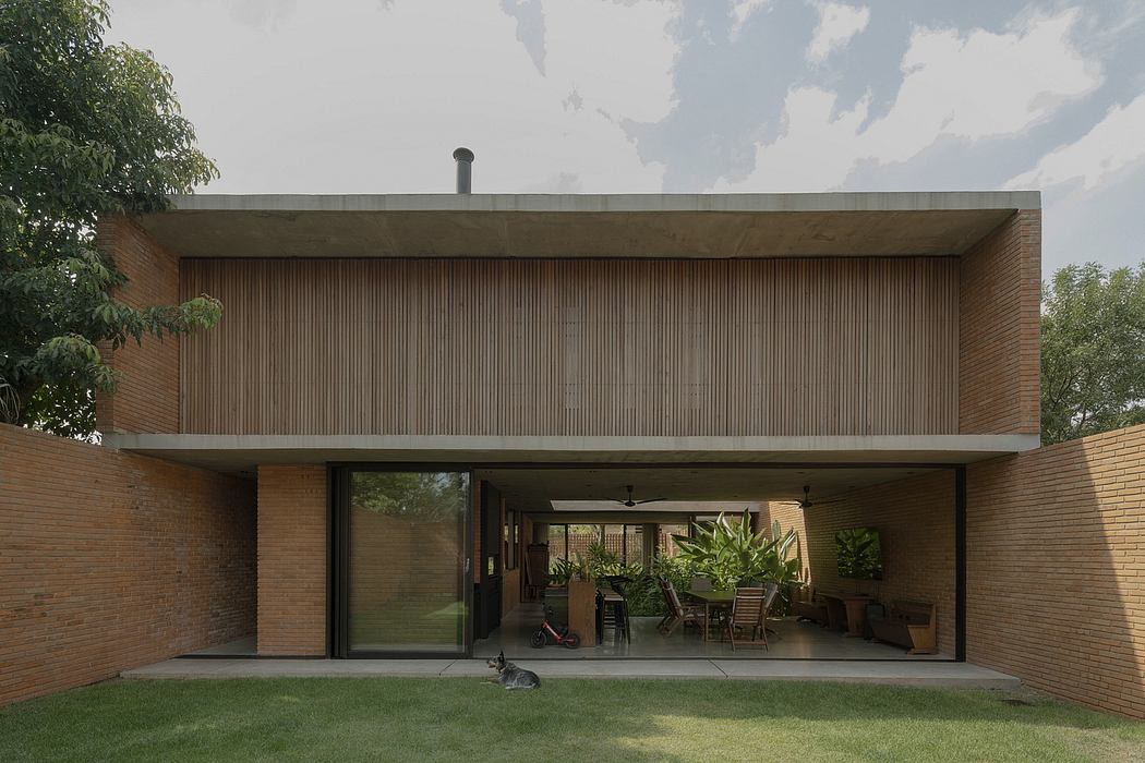 A modern brick and wood house with a large covered patio and lush greenery.