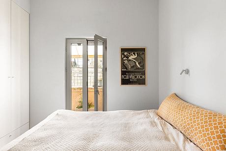 Minimal modern bedroom with glass doors leading to outdoor space; vintage film poster.