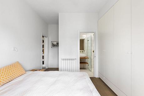 Bright, minimalist bedroom with white walls, built-in storage, and en-suite bathroom.