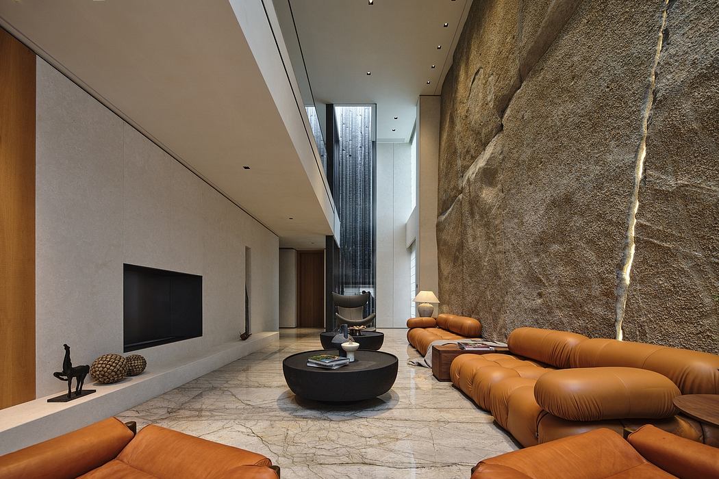 Spacious modern living room with natural stone walls, leather sofas, and minimalist decor.