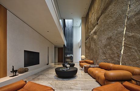 Spacious modern living room with natural stone walls, leather sofas, and minimalist decor.