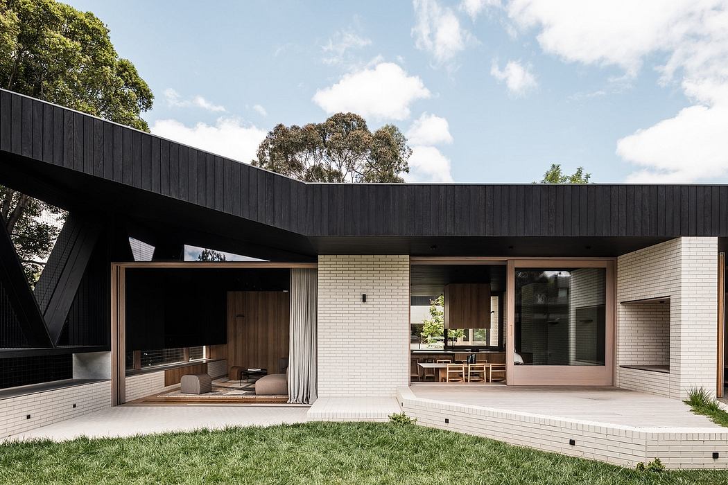 Modern single-story home with minimalist black exterior, large windows, and wooden accents.