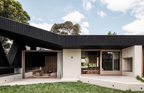 Modern single-story home with minimalist black exterior, large windows, and wooden accents.