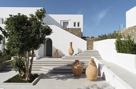 Minimalist Mediterranean architecture with ornate pottery and lush greenery.