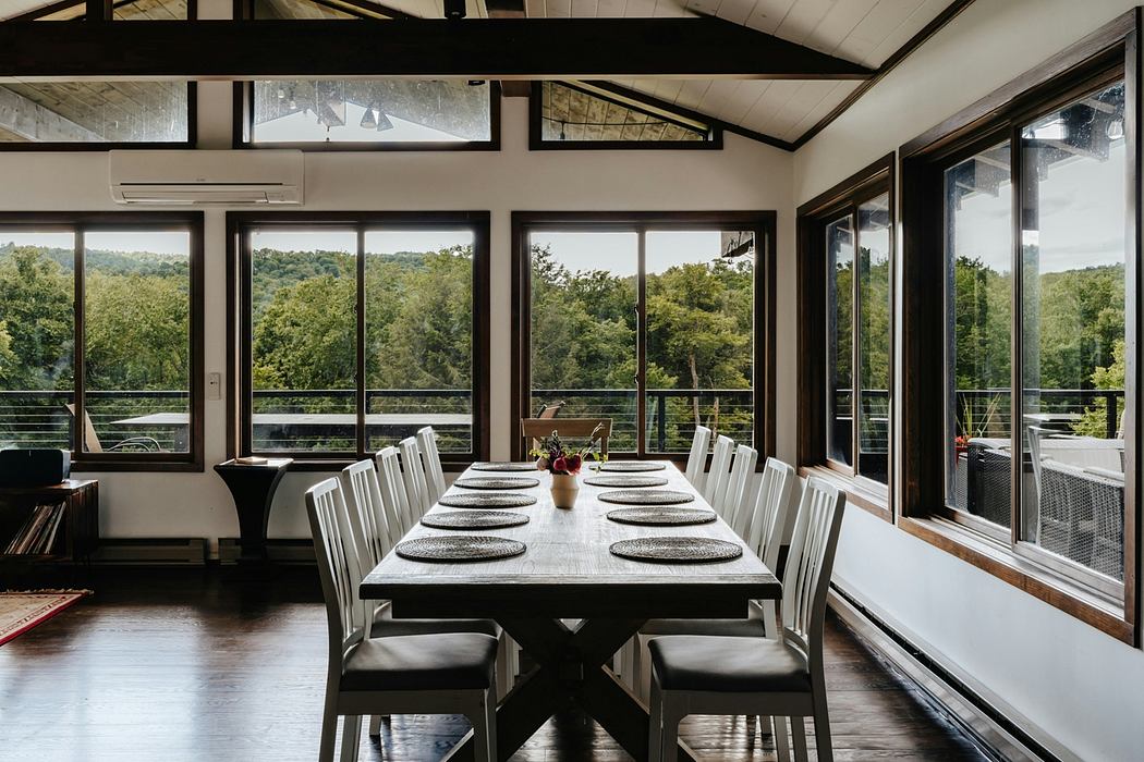 Spacious dining room with vaulted ceilings, large windows, and rustic wooden furniture.