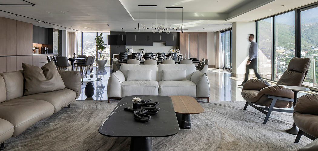 Spacious, modern living area with large windows, grey sofas, and a sleek, minimalist design.
