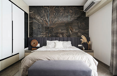 Modern, minimalist bedroom with striking black marble accent wall, plush gray upholstered headboard, and sleek built-in nightstands.