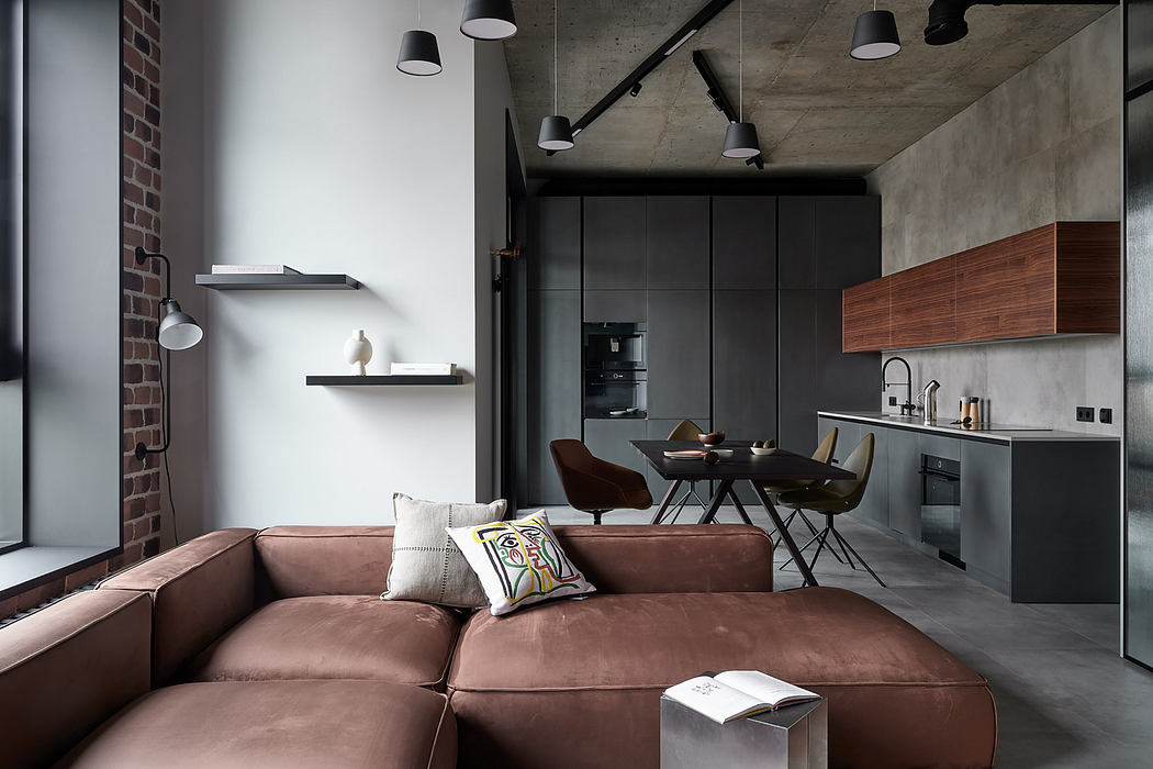 An industrial-style loft with concrete walls, hanging lamps, and a brown leather sofa.