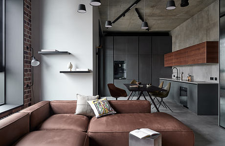 An industrial-style loft with concrete walls, hanging lamps, and a brown leather sofa.