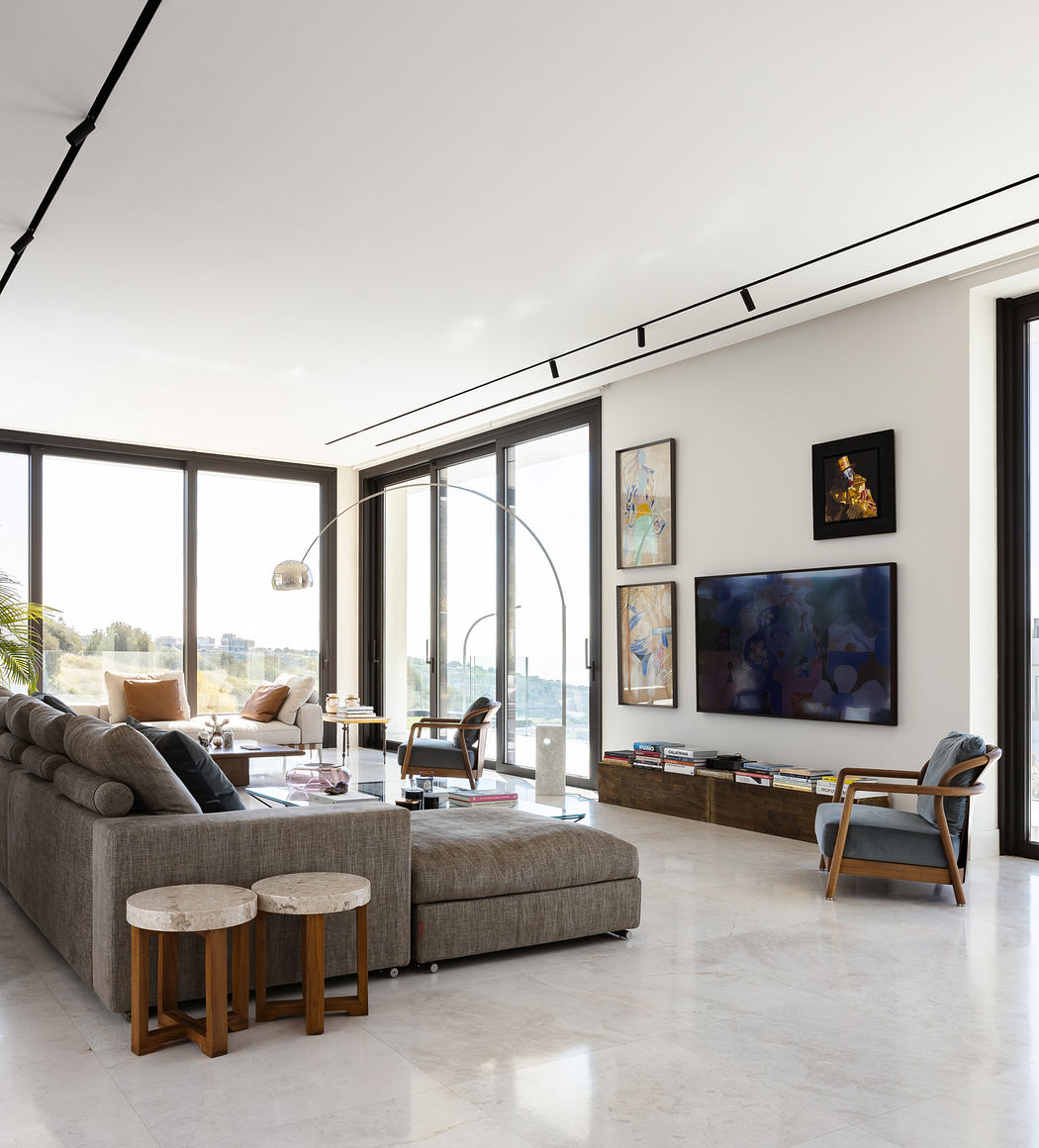 Spacious, modern living room with large windows, artwork, and minimalist furnishings.