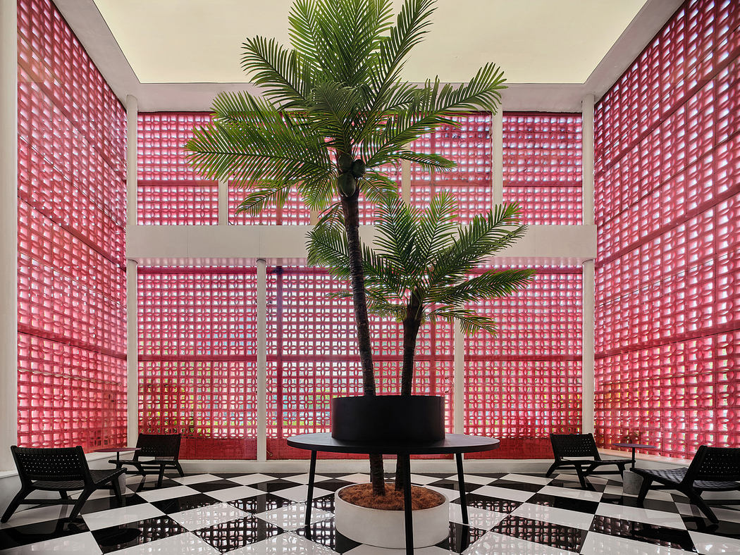 Striking architectural space featuring vibrant pink latticed walls, potted palm tree, and checkered floor.
