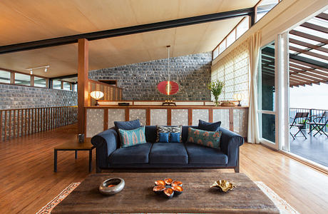 Large room with wooden ceiling, stone walls, and cozy navy blue sofa with colorful pillows.