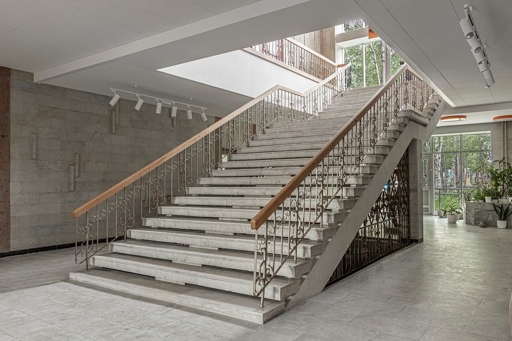 Ornate staircase with metal railings in modern concrete and glass building.
