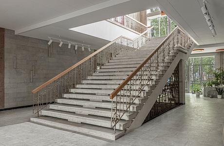 Ornate staircase with metal railings in modern concrete and glass building.