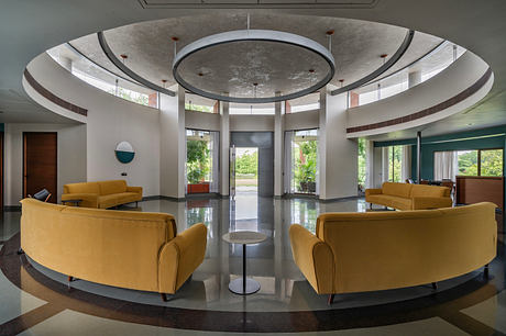 Sleek, modern lobby with curved ceiling, circular lighting, and plush yellow seating.