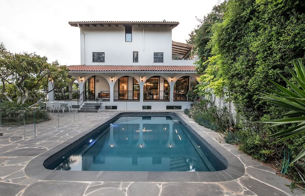 A Spanish-style villa with a tile roof, arched windows, and a stunning in-ground pool.