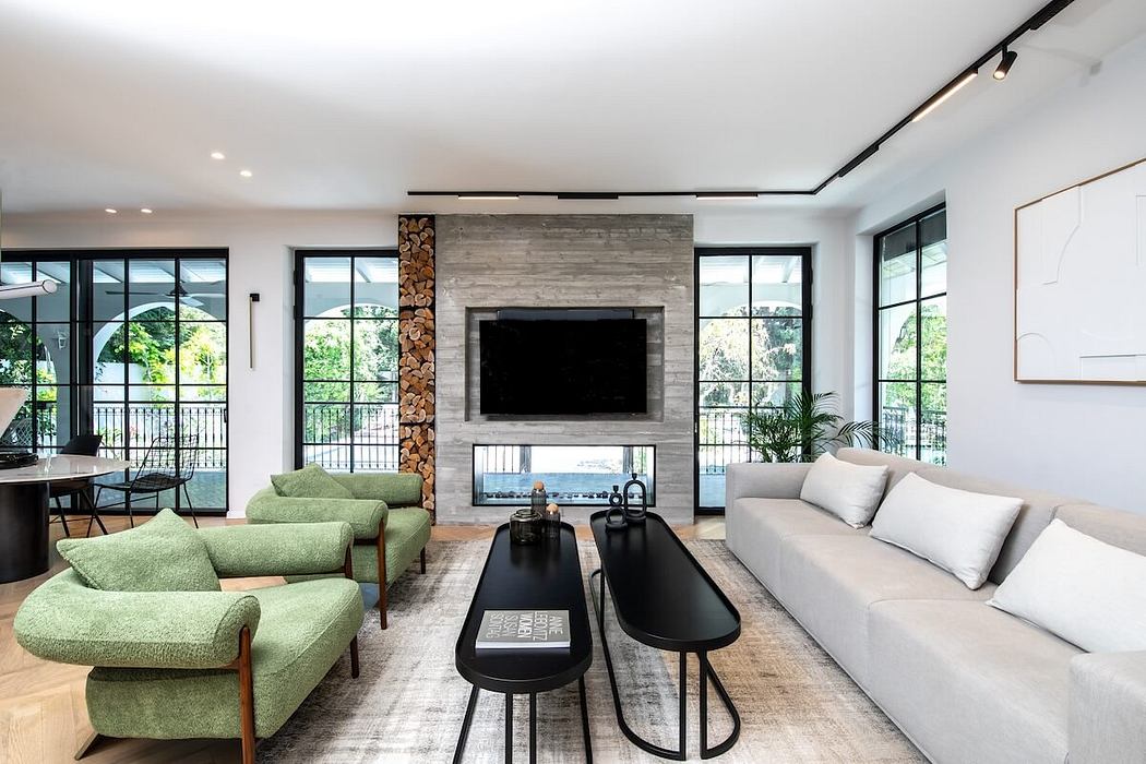 Spacious modern living room with large windows, fireplace, and green upholstered furniture.