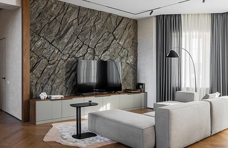 Sleek, contemporary living room with a striking stone accent wall, minimalist furniture, and hardwood flooring.