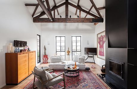 Spacious living room with exposed wooden beams, plush furnishings, and eclectic decor.
