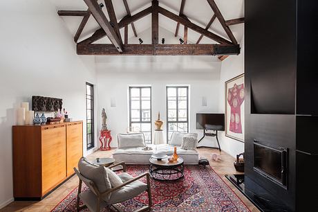 Spacious living room with exposed wooden beams, plush furnishings, and eclectic decor.