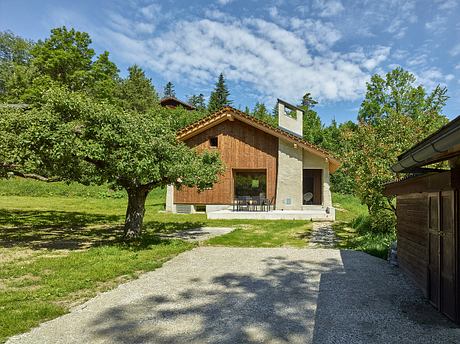 A rustic wooden cabin nestled in a lush, green landscape with a peaceful patio.