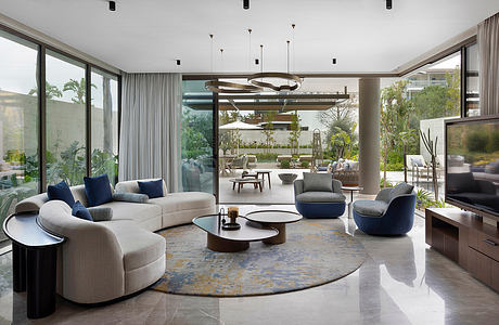 Luxurious open-plan living space with sleek furnishings, pendant lights, and lush outdoor views.