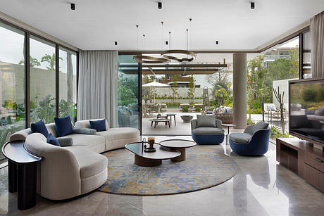 Luxurious open-plan living space with sleek furnishings, pendant lights, and lush outdoor views.