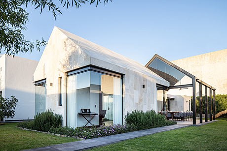 Modern, minimalist exterior with large glass windows, stone facade, and lush landscaping.